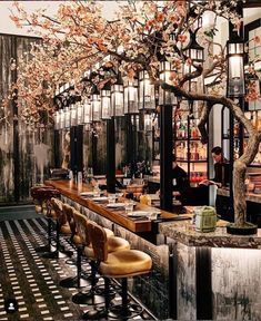 an empty restaurant with tables and stools next to a tree in front of the bar