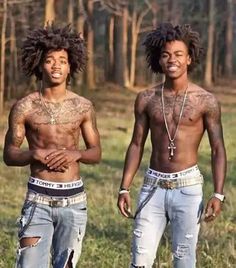 two young men standing next to each other in front of some trees with tattoos on their chestes