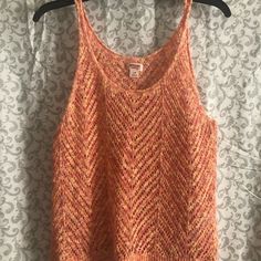 an orange tank top hanging on a wall