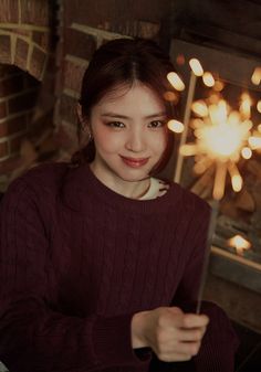 a woman holding a sparkler in front of a fireplace