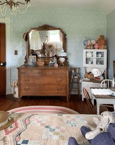 an old fashioned dresser and mirror in a room with blue wall paper on the walls