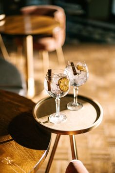 two wine glasses sitting on top of a table next to each other in front of a chair