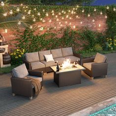 an outdoor fire pit surrounded by wicker chairs and tables with lights strung over it