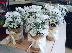 some white daisies are in small baskets on a wooden table and tied with twine