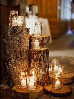 candles are lit in mason jars on wood slices