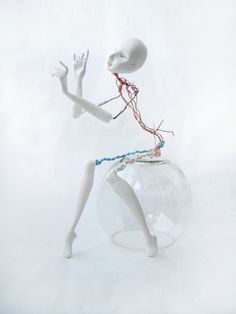 a white mannequin sitting on top of a glass ball with wires attached to it