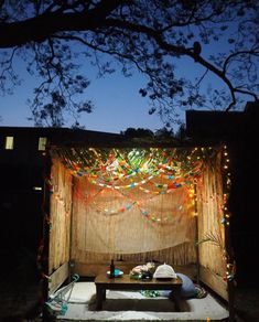 an outdoor stage set up with lights and curtains on the outside, at night time