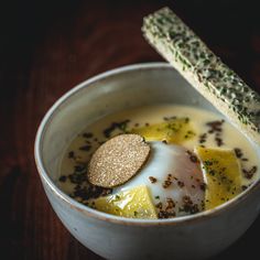 a bowl filled with soup and bread on top of a wooden table