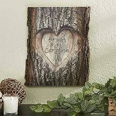 a wooden heart hanging on the wall next to a candle and some potted plants