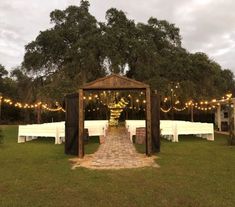 an outdoor wedding venue set up with white linens and lights on the trees in the background