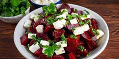 a bowl filled with beets and feta cheese on top of a wooden table