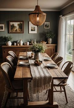 a dining room table with plates and place settings on it, in front of a large window