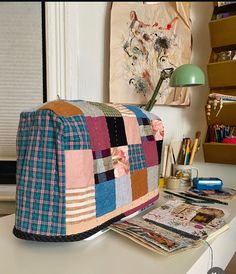 a colorful patchwork bag sitting on top of a white desk next to a lamp