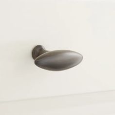 a door handle on the side of a white cabinet with an oval knob in it