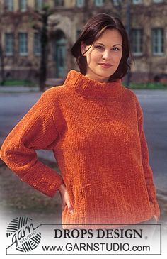 the woman is wearing an orange sweater and posing in front of a building with her hands on her hips