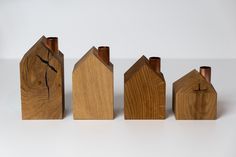 four wooden houses are lined up on a white surface