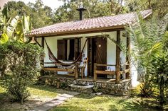 a small white house with hammocks on the porch