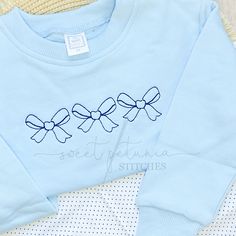 a blue sweater with three bows on it