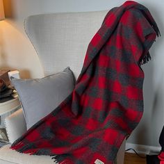 a red and black plaid blanket sitting on top of a couch next to a lamp