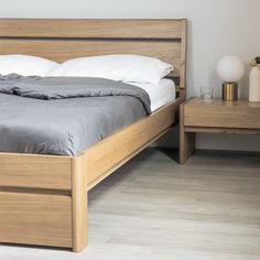 a bed with two nightstands next to it in a room that has white walls and wood flooring