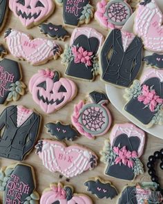 decorated cookies are arranged on a table with pink and black decorations in the shape of bride and grooms