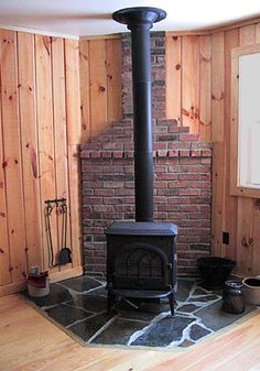 a wood burning stove in a room with wooden paneling