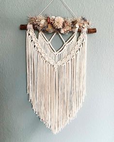 a macrame hanging on the wall with flowers