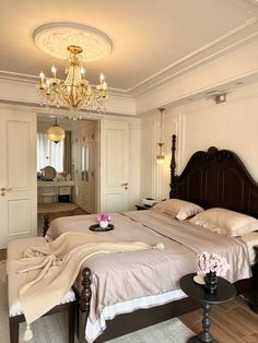 a bedroom with a large bed, chandelier and two tables in front of it