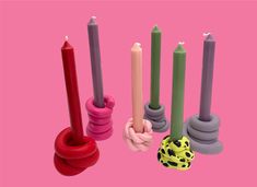 several candles with different shapes and sizes on a pink background