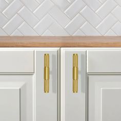 a kitchen with white cabinets and gold handles