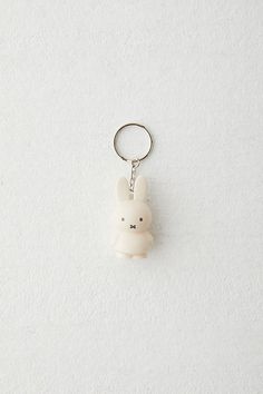 a keychain with a small white teddy bear on it's front and back ends