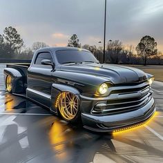 a black truck with yellow lights on it's hood in a parking lot at dusk