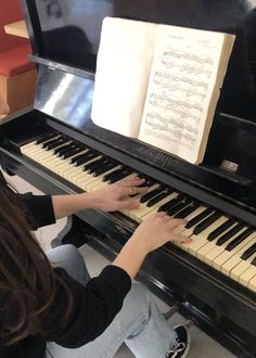 a woman sitting at a piano playing an old fashioned musical instrument with sheet music on it