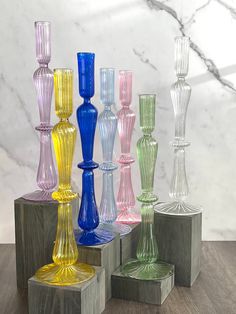 there are many different colored glass vases on the stand together in front of a marble wall