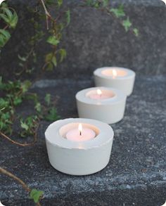 three white candles are sitting on the ground