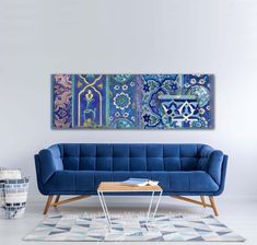 a blue couch sitting in front of a painting on the wall next to a coffee table