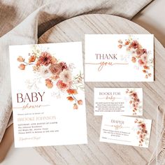 the wedding stationery is laid out on top of a wooden table with flowers and greenery