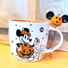 a mickey mouse mug with a jack - o'- lantern on it