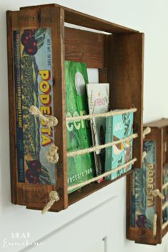 two wooden boxes with rope hanging from the sides, each holding books and other items