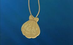 a gold necklace with an image of a shell hanging from it's side on a blue background