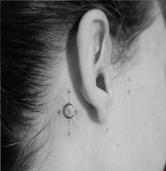 a woman's behind the ear has a small star and moon tattoo on it