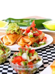 some tacos and guacamole are sitting on a checkered tablecloth