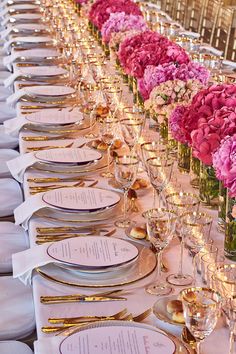 a long table is set with place settings and flowers in vases on each side