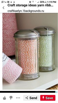 two jars with spools of twine on top of a shelf next to yarn