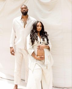 a man and woman standing next to each other in front of a white backdrop,