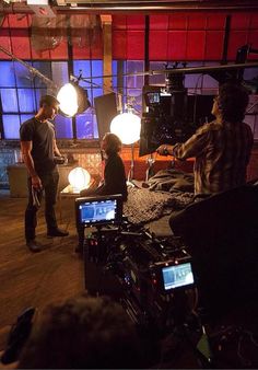 two men standing in front of a camera set up for a video shoot with lights on