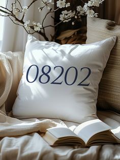 a pillow with the number 0802 on it next to an open book and flowers