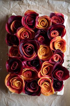 an arrangement of rolled paper flowers on top of a piece of waxed paper,