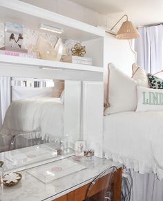 a white bed sitting next to a desk with a mirror on the top of it