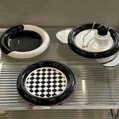 three black and white plates sitting on top of a metal counter next to each other